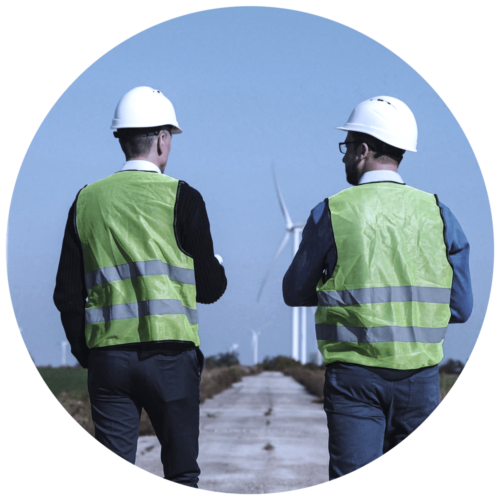 Two men in security vests at a wind farm talking together